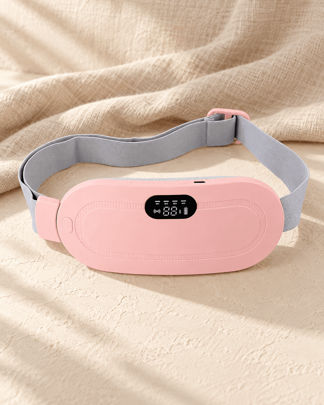 The Period Reset Belt in blush, laid on a warm cream surface with folded linen behind it